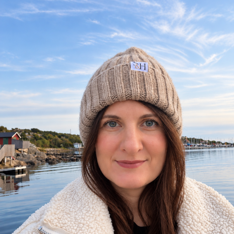 Kvinna bär FREJA-mössa i Sand med vävd S&H-etikett