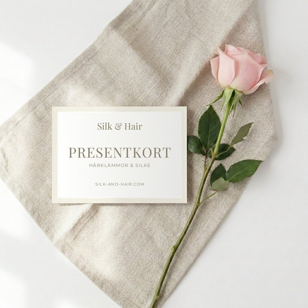 Presentkort från Silk & Hair på en linneduk med en rosa ros